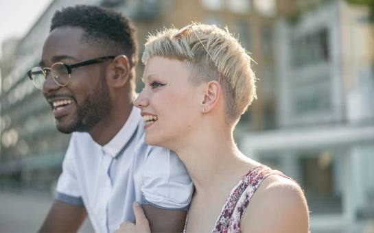 A smiling couple. The man is wearing glasses.